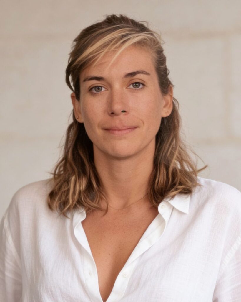 Portrait of Sarah Rowland in a white linen shirt against a pale stone wall