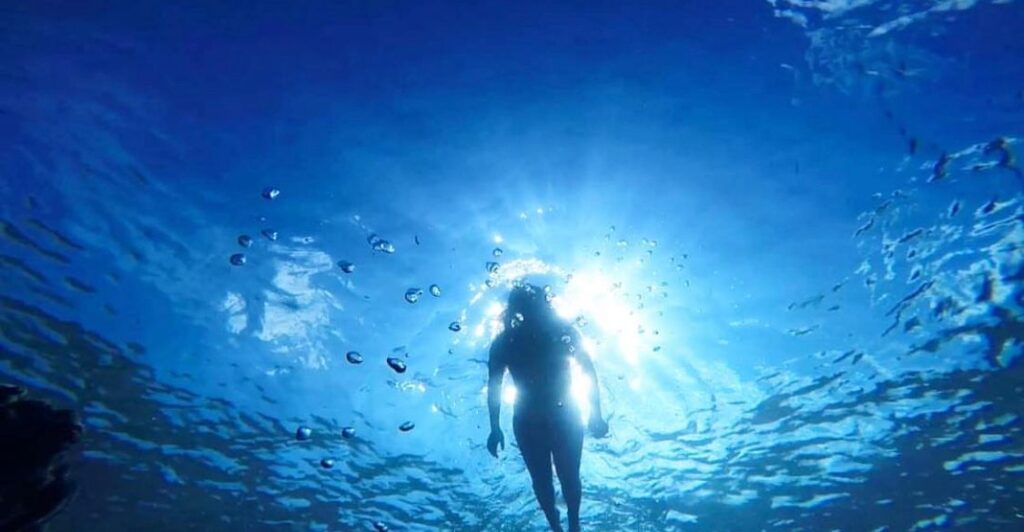 Swimmer seen from below the surface in clear Caribbean water
